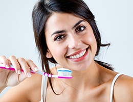young woman smiling while holding toothbrush 