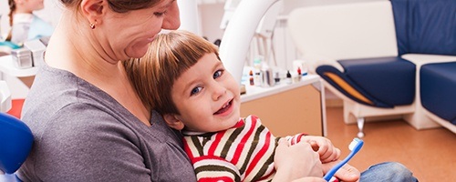 Mother holding smiling child in dental chair