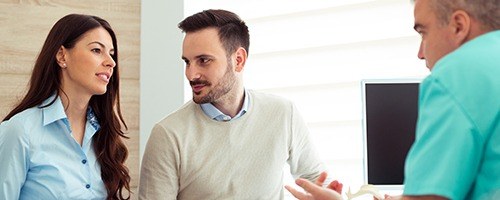 Man and woman talking to dental team member