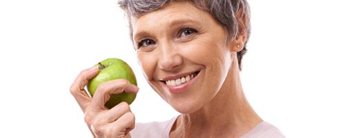 smiling senior woman holding a green apple