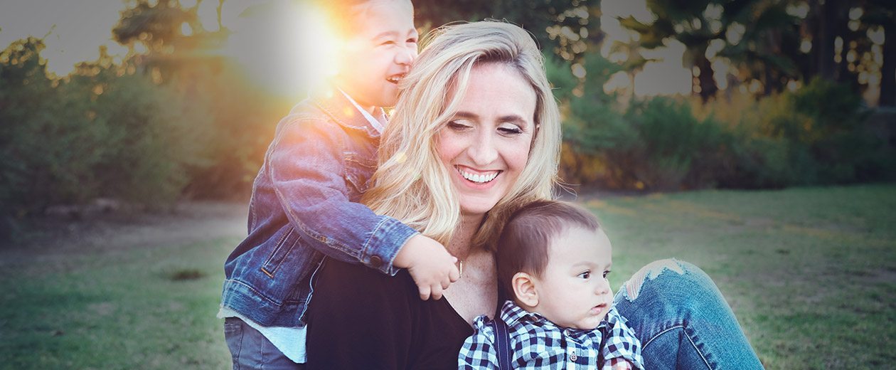 Smiling woman and two young children outdoors