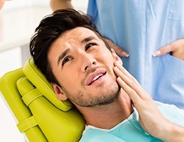 Man in dental chair holding jaw