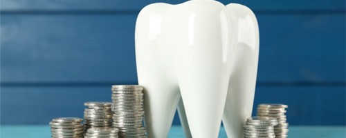 A ceramic model tooth amid stacks of coins