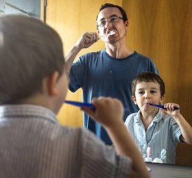 A father and son brushing their teeth together