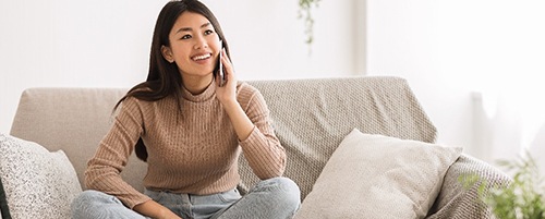 person smiling and talking on their phone while sitting on a couch