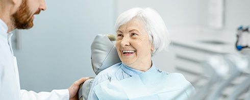 Patient with dentures smiling at dentist