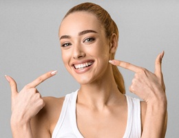 A young woman pointing at her smile