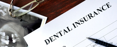 A piece of paper that reads “Dental Insurance” with x-rays, glasses, money, and a pen