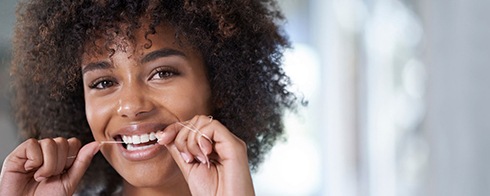 woman flossing to prevent dental emergencies in Mesquite 