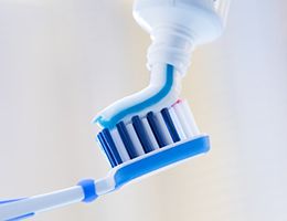 toothpaste being put onto a blue toothbrush 