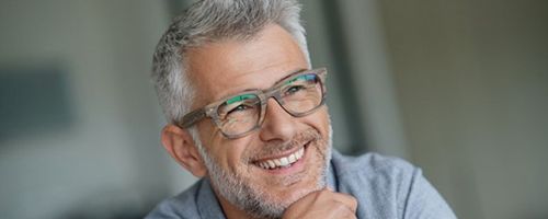 older man smiling after getting professional teeth whitening from dentist 