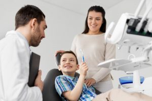 little boy holding toothbrush in dental chair 