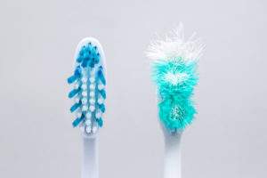 Old and new toothbrush standing side-by-side