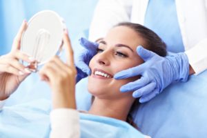 woman admiring her smile in hand mirror after professional teeth whitening 