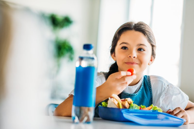 Happy child eating her lunch at school