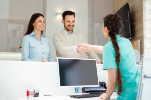 dental team member shaking hands with patient at front desk