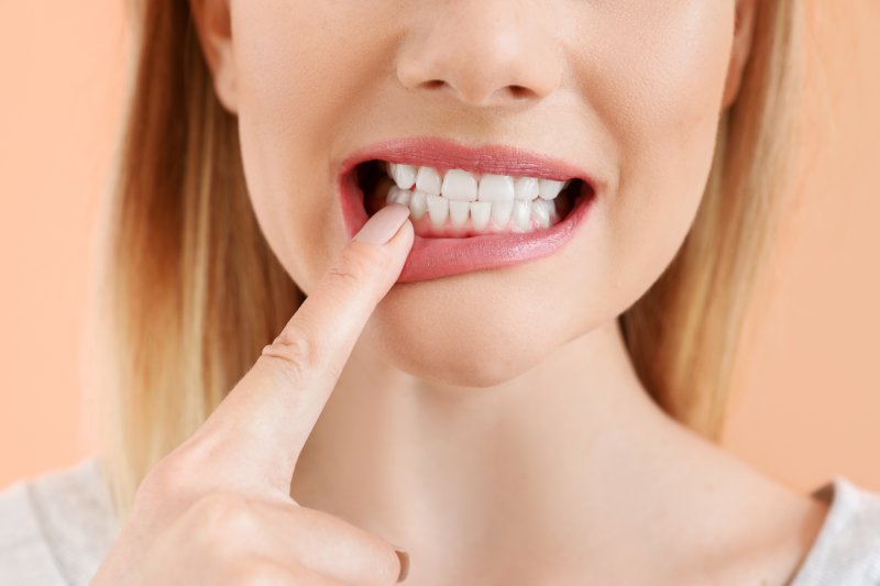 an up-close view of a person pointing to a tooth in the lower arch of their mouth