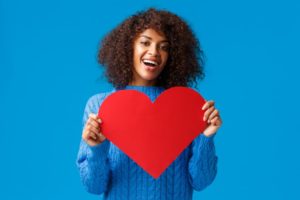 woman smiling and holding a heart