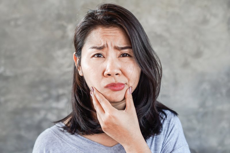 Woman with facial swelling rubbing chin in pain