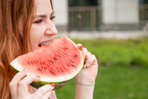 a young woman wearing braces and eating watermelon during the summer
