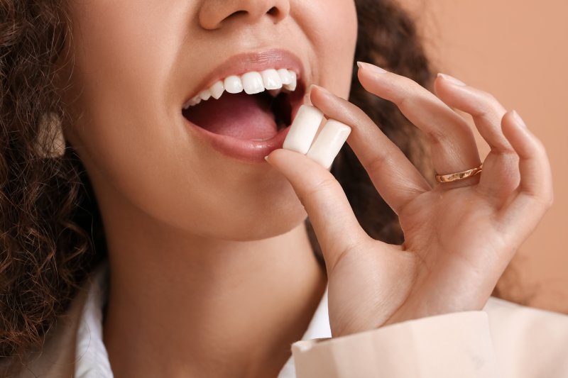 woman holding chewing gum near her mouth