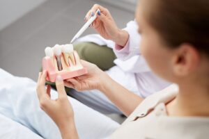 Dentist showing model dental implant to a patient