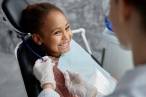 Little girl in pink sweater in dentist's chair smiling