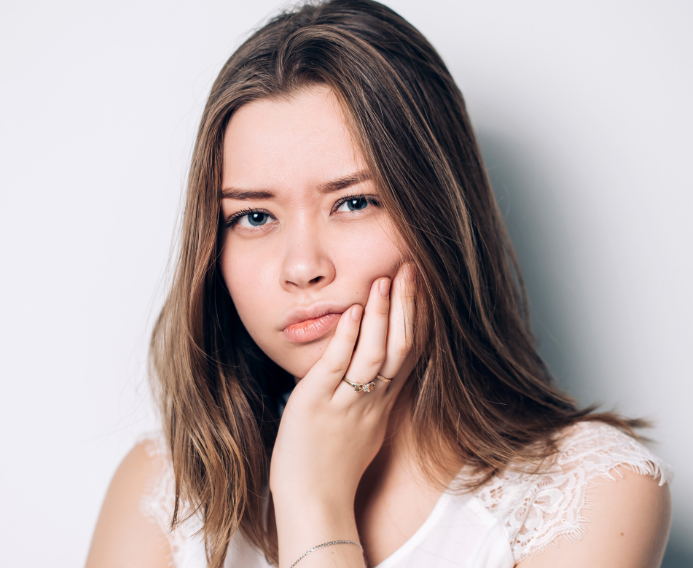 Girl holding side of face, frowning in pain.